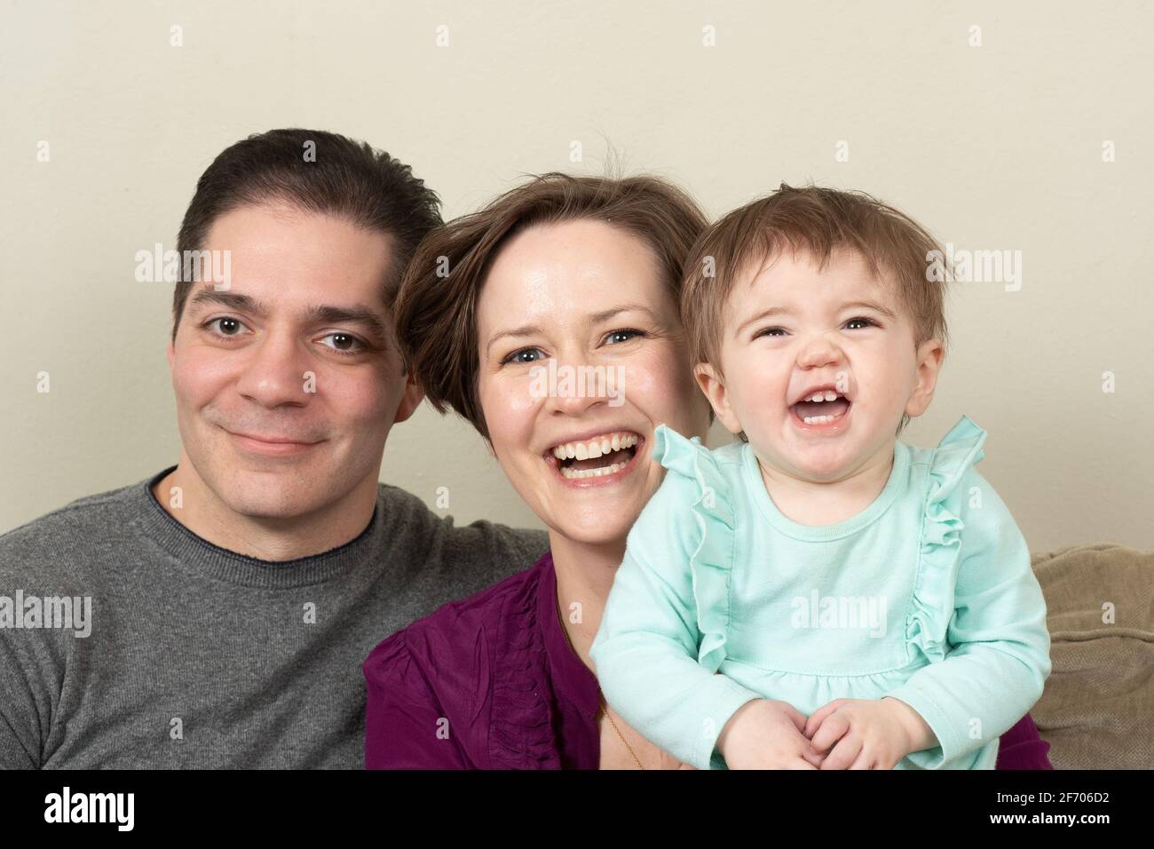bambino ragazza di 10 mesi ridendo felice closeup ritratto di famiglia con i suoi genitori Foto Stock