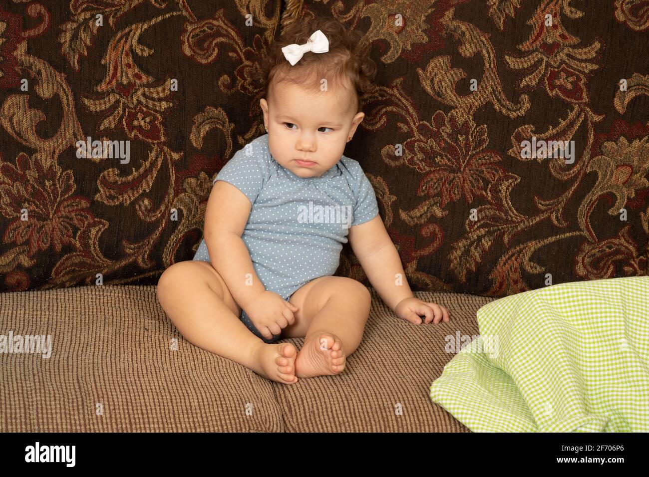 Sequenza di permanenza oggetto Piaget due di due bambina di 7 mesi seduta sul divano guardando via, indifferente dopo che il giocattolo è coperto con mancanza di stoffa di o Foto Stock