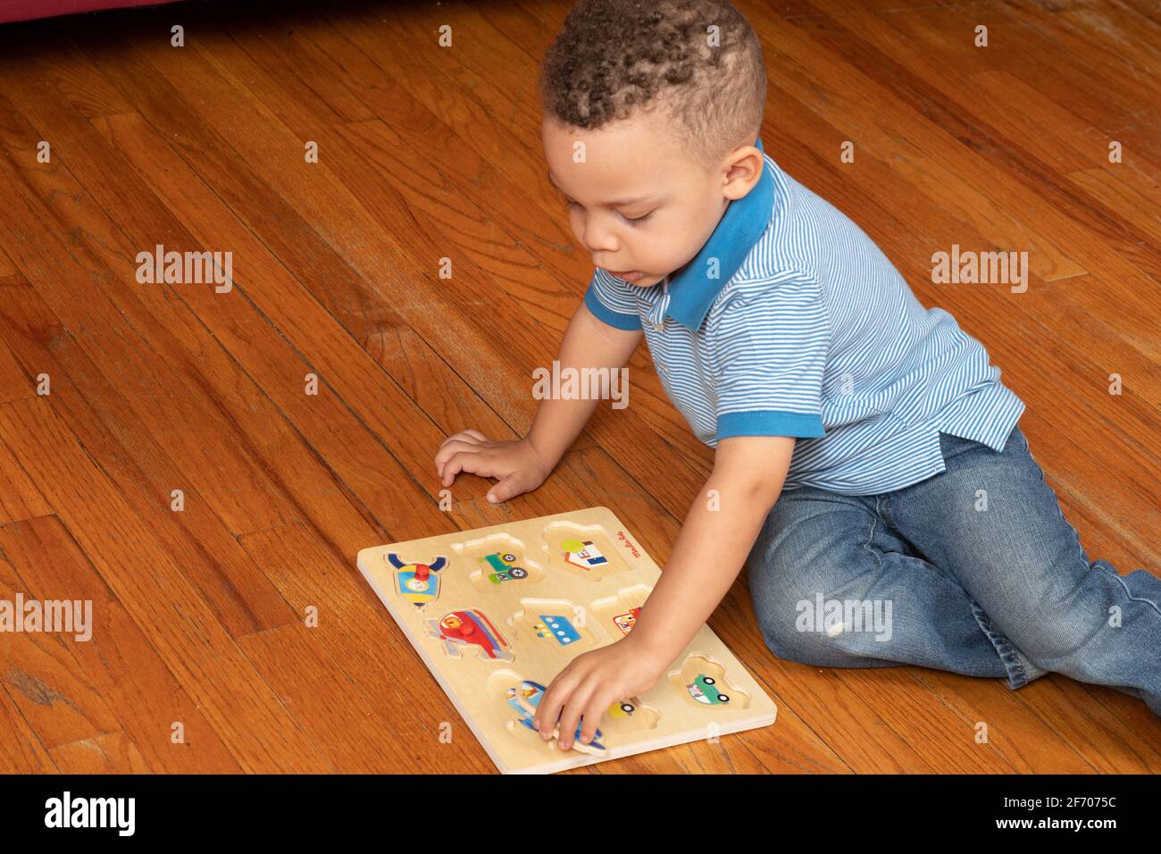 ragazzo di 3 anni che fa in legno peg puzzle mostrando veicoli, tema del trasporto Foto Stock
