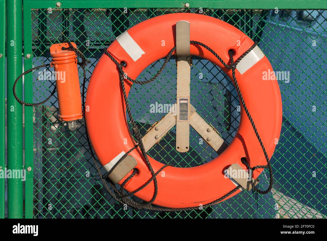Anello di emergenza arancione non marcato su una barca commerciale contro uno sfondo verde Foto Stock