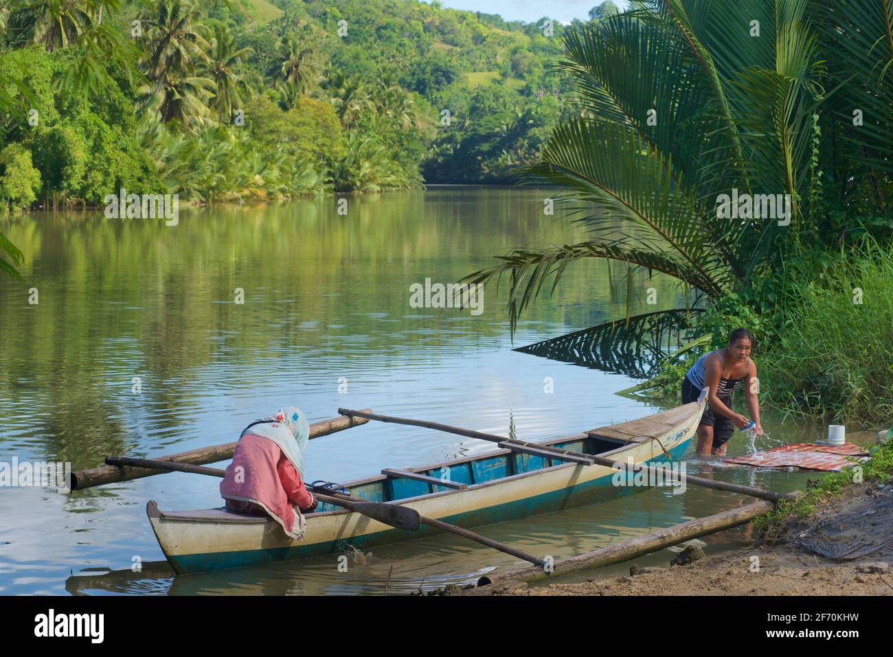 Piccola canoa Outrigger per traversate del fiume come un traghetto locale. Lavaggio nel fiume. Fiume Loboc, Bohol, Visayas Centrale, Bohol, Filippine. Foto Stock