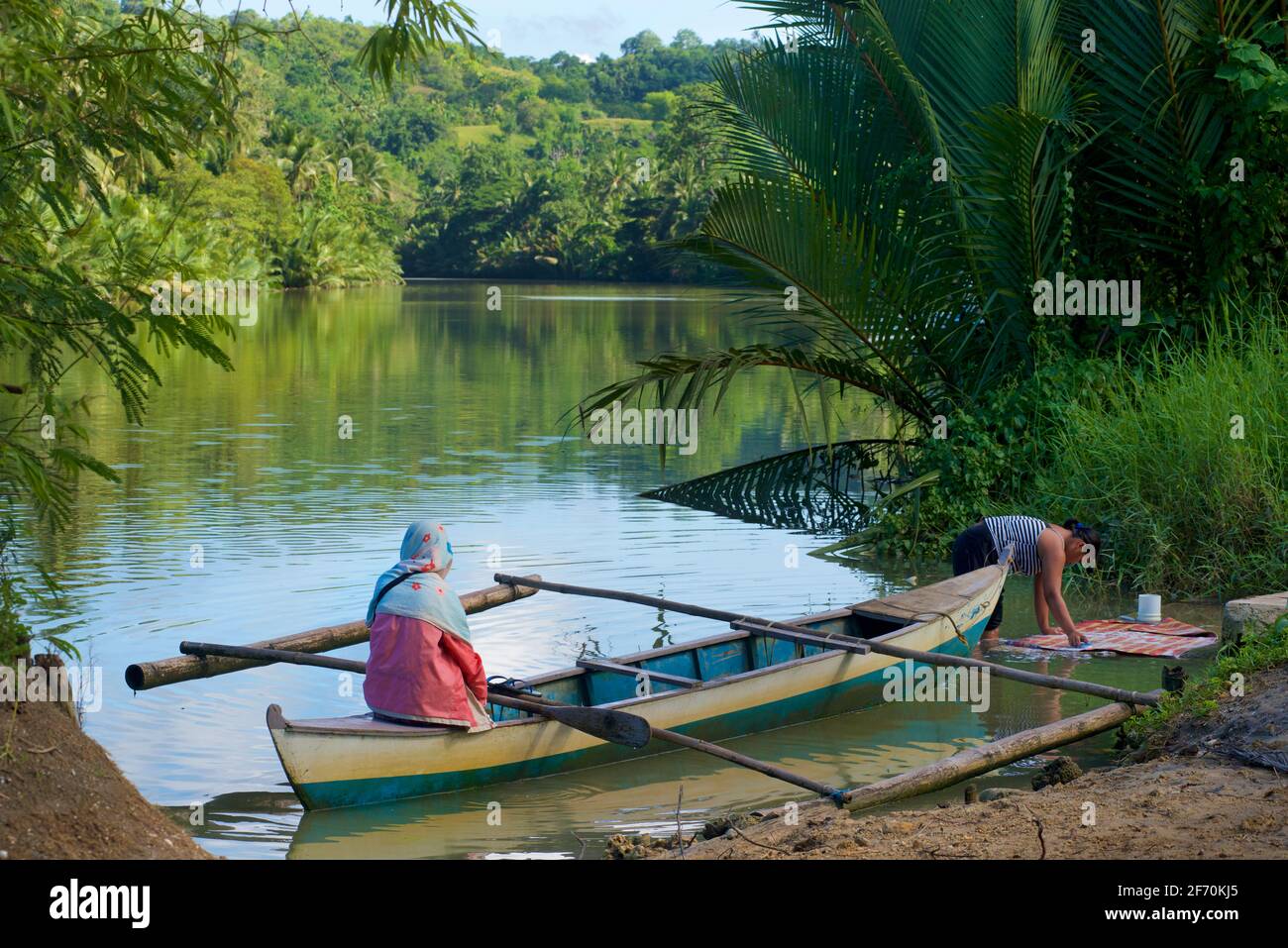 Piccola canoa Outrigger per traversate del fiume come un traghetto locale. Lavaggio nel fiume. Fiume Loboc, Bohol, Visayas Centrale, Bohol, Filippine. Foto Stock