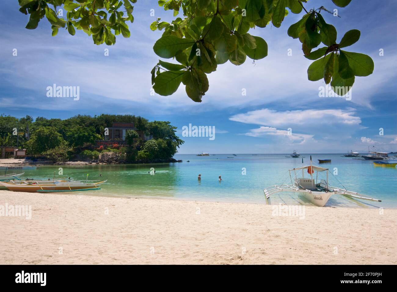 La baia di Logon, isola di Malapascua, con canoa Outrigger sulla spiaggia di sabbia bianca. Mare di Visayan, Cebu, Filippine. Foto Stock