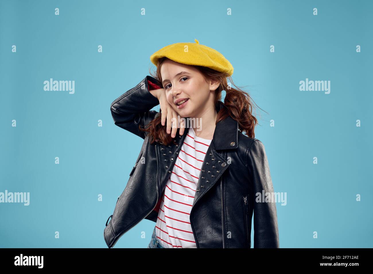 Ragazza alla moda in beretta gialla e giacca in pelle a strisce T-shirt  sfondo blu Foto stock - Alamy