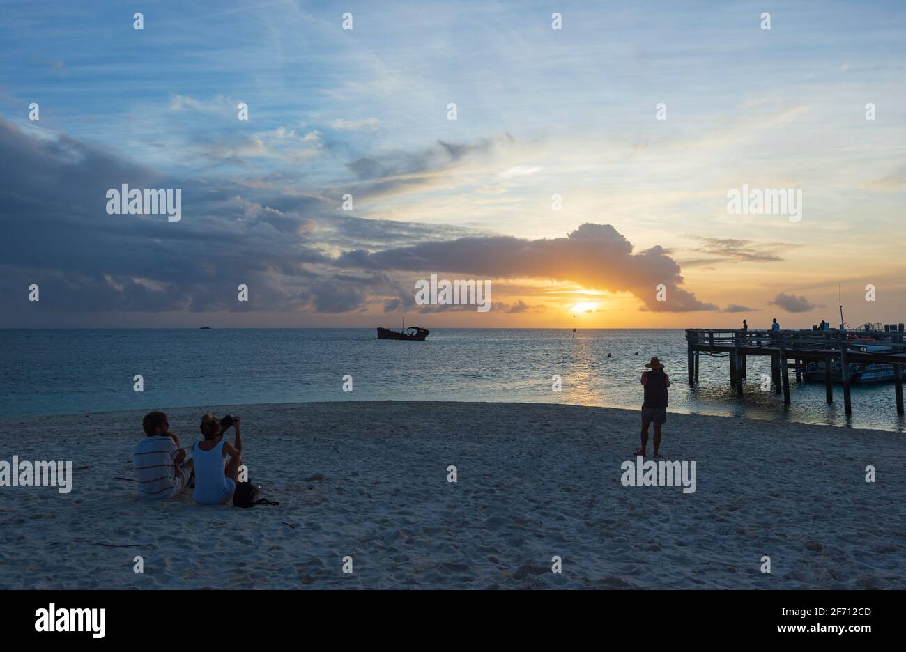 Turista sulla spiaggia guardando il tramonto sul Mare dei Coralli a Heron Island, Grande barriera Corallina Meridionale, Queensland, QLD, Australia Foto Stock