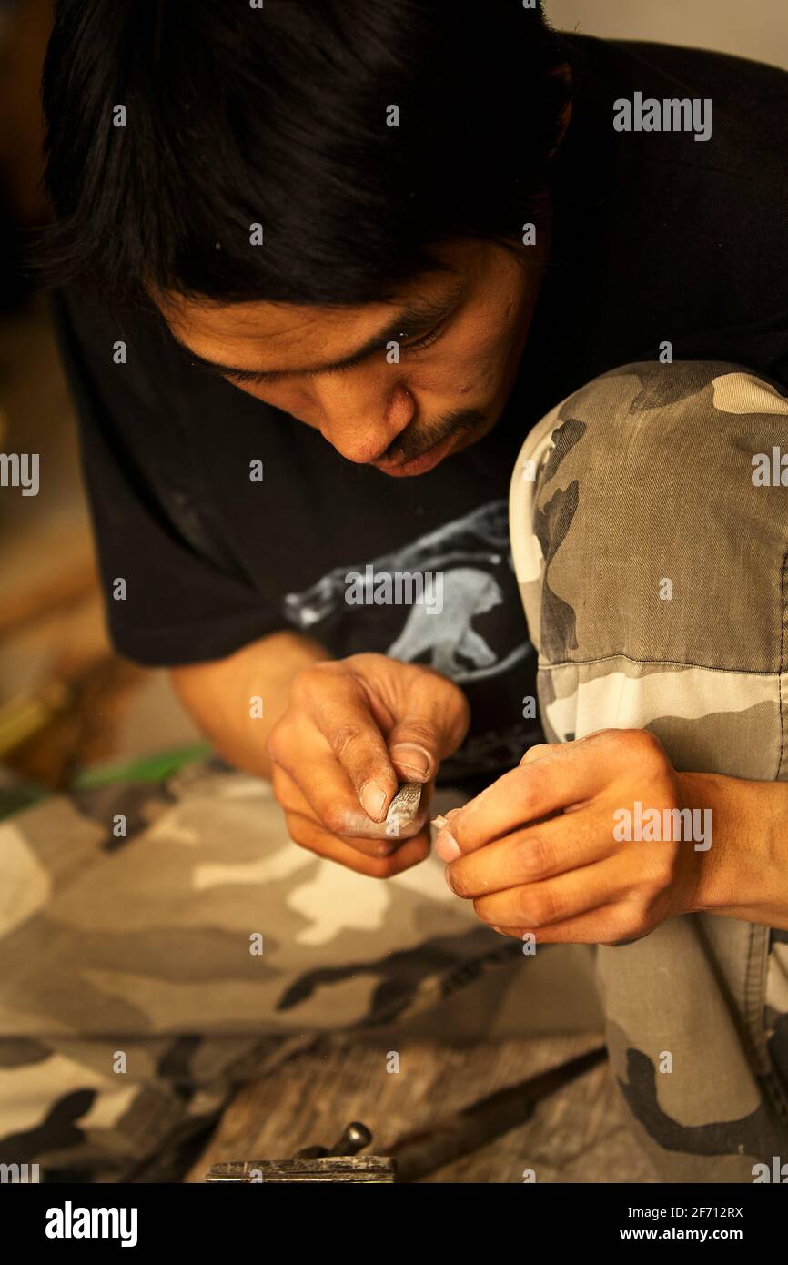 L'artista Inuit taglia e limando l'osso di cariboo per creare la base per le balene narwhali da montare anche. Foto Stock