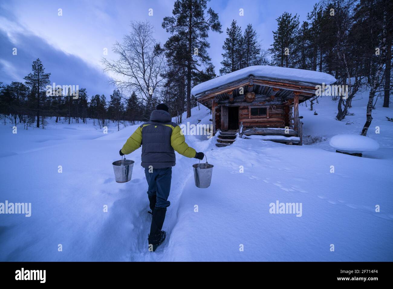 Portare l'acqua alla sauna presso la baita aperta Anterinmukka, Sodankylä, Lapponia, Finlandia Foto Stock