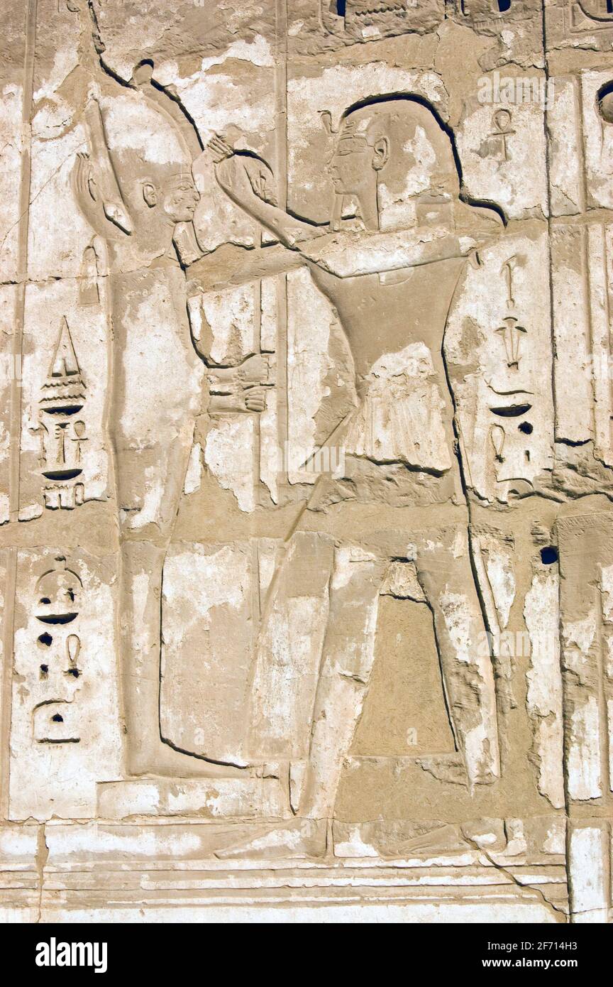 Un'antica scultura geroglifica egiziana del faroah Ramses II con il dio creatore Ptah. Muro di pietra al Tempio di Medinet Habu sulla riva occidentale Foto Stock