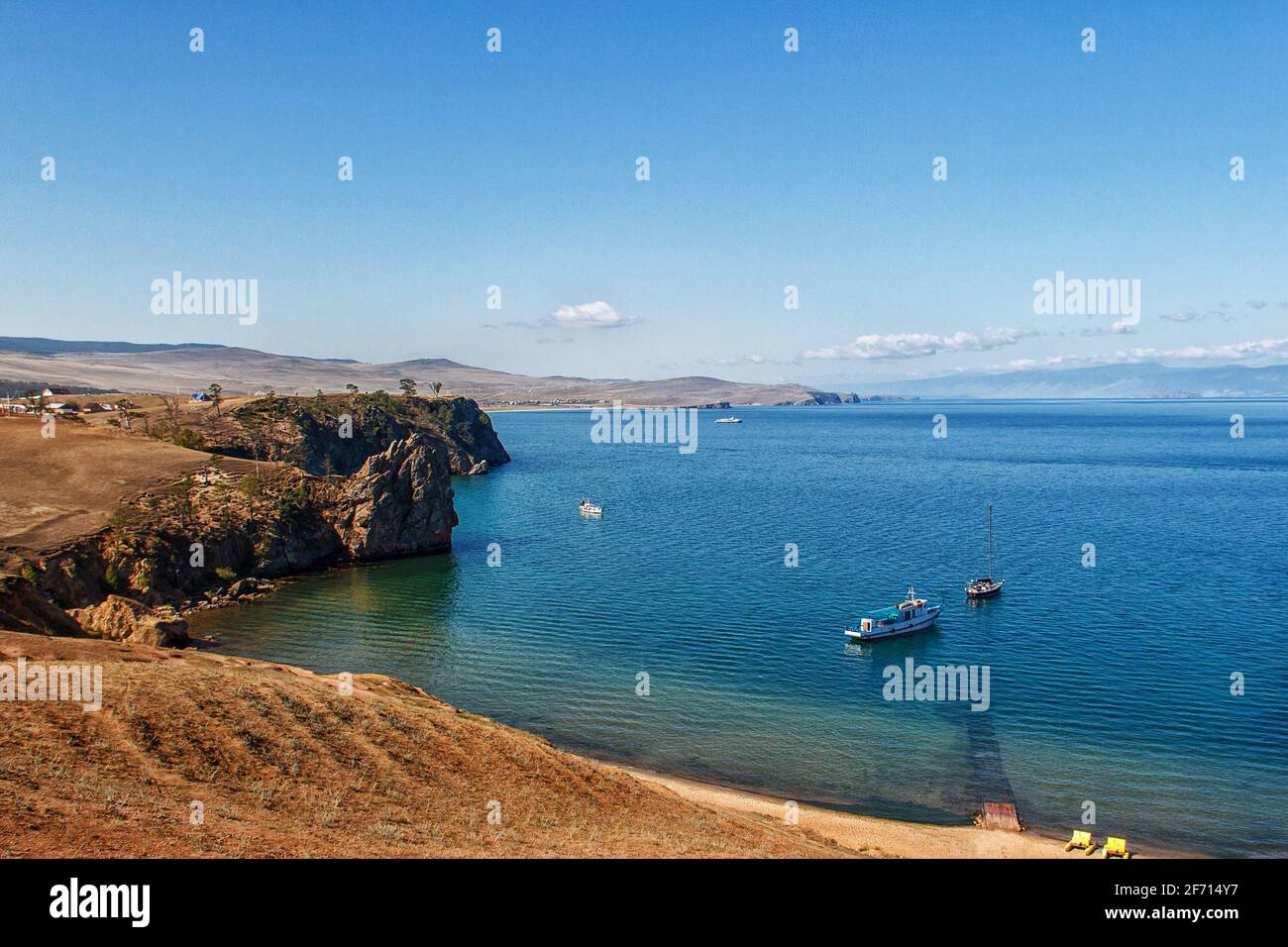 Paesaggio con l'immagine della costa rocciosa del lago Baikal e barche. Vista sul lago dall'isola di Khuzhir Foto Stock