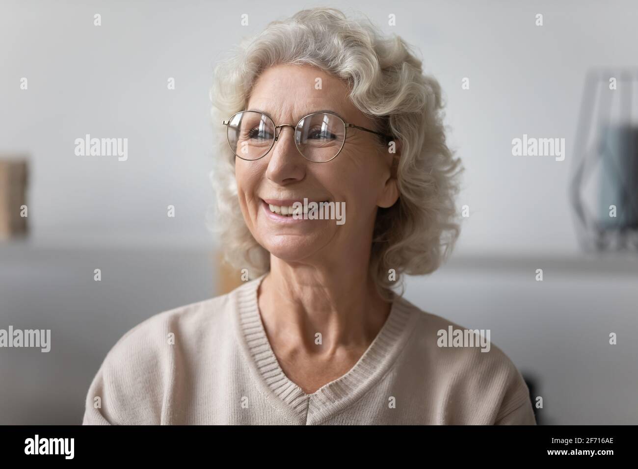 Felice anziana signora pensiva indossare occhiali, guardando la finestra Foto Stock