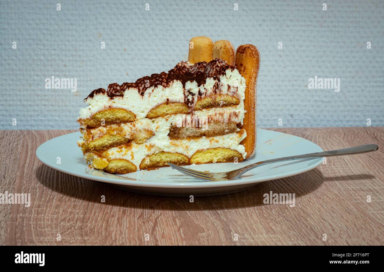 Pezzo di torta di Tiramisu con ladyfingers, panna montata e polvere di cioccolato su un piatto Foto Stock