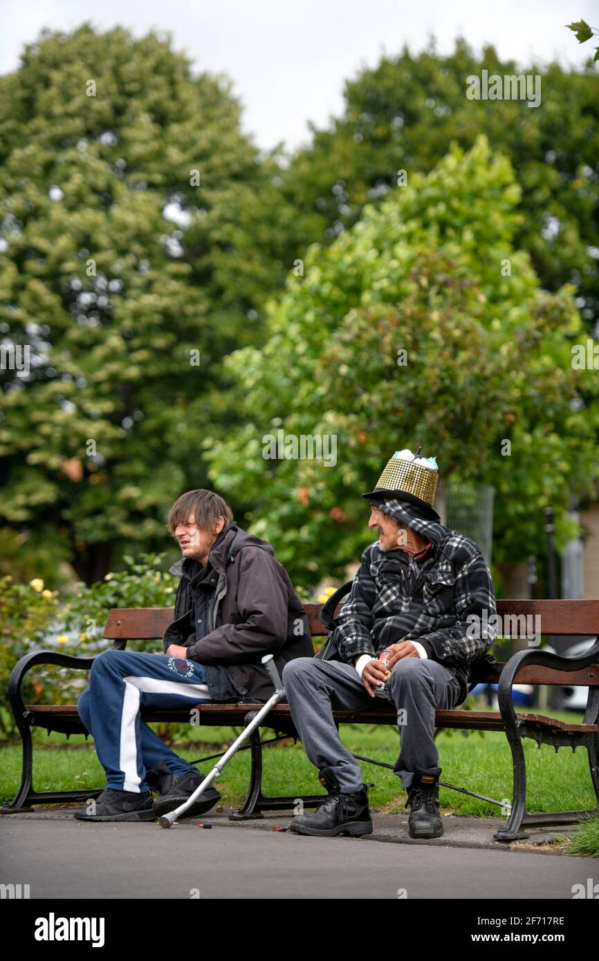 Due uomini su una panchina del parco a Brunswick Square, Bristol, Regno Unito Foto Stock