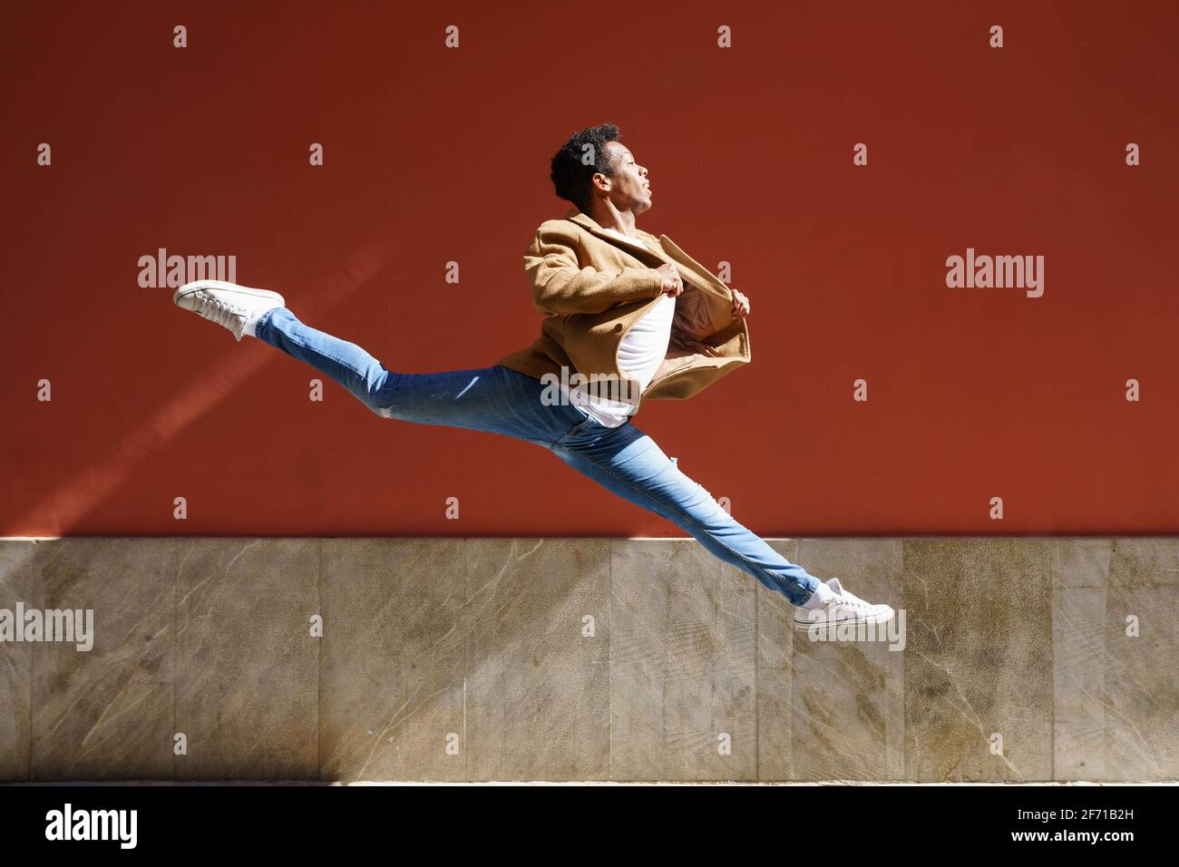 Uomo nero atletico che fa un salto acrobatico all'aperto Foto Stock