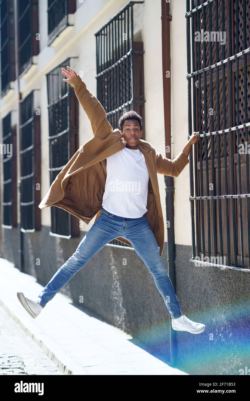Giovane uomo nero che salta su una griglia della finestra nella strada. Foto Stock