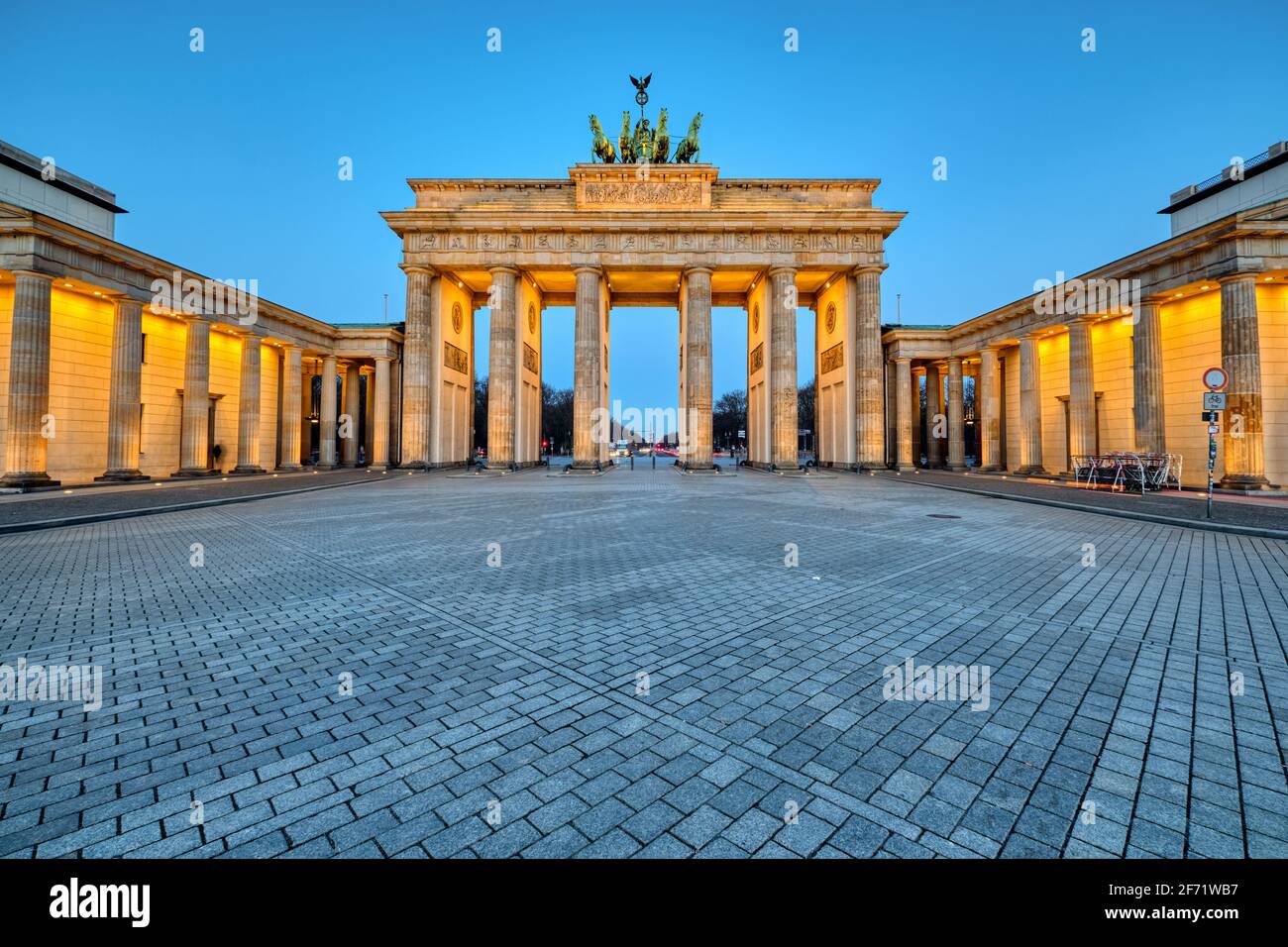 La porta di Brandeburgo illuminata a Berlino all'alba Foto Stock