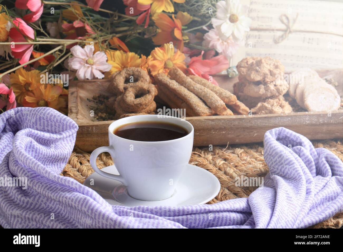 Una tazza mattutina di caffè caldo con fiori e musica. Foto Stock