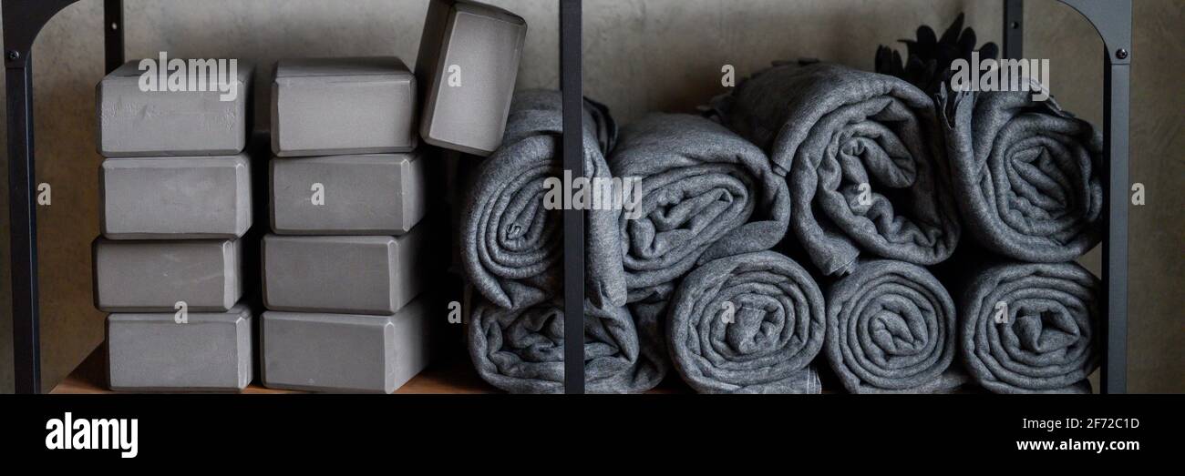 l'interno della sala è uno studio per lo yoga sportivo o lo stretching. tavolo con accessori per le lezioni - cubi di sostegno grigio, tappetini in gomma e plai Foto Stock