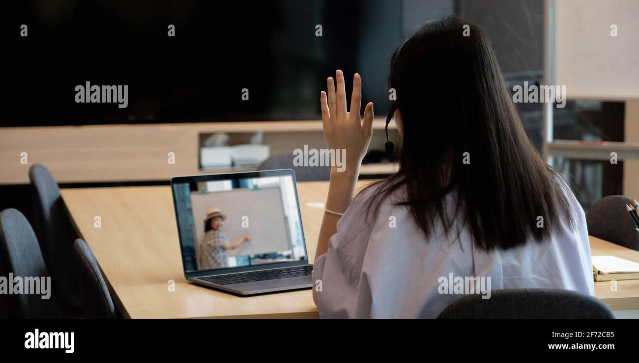 Giovane studentessa asiatica che impara il Internet virtuale classe online da insegnante di scuola da remoto riunione a causa della pandemia di covid. Insegnamento femminile tramite Foto Stock
