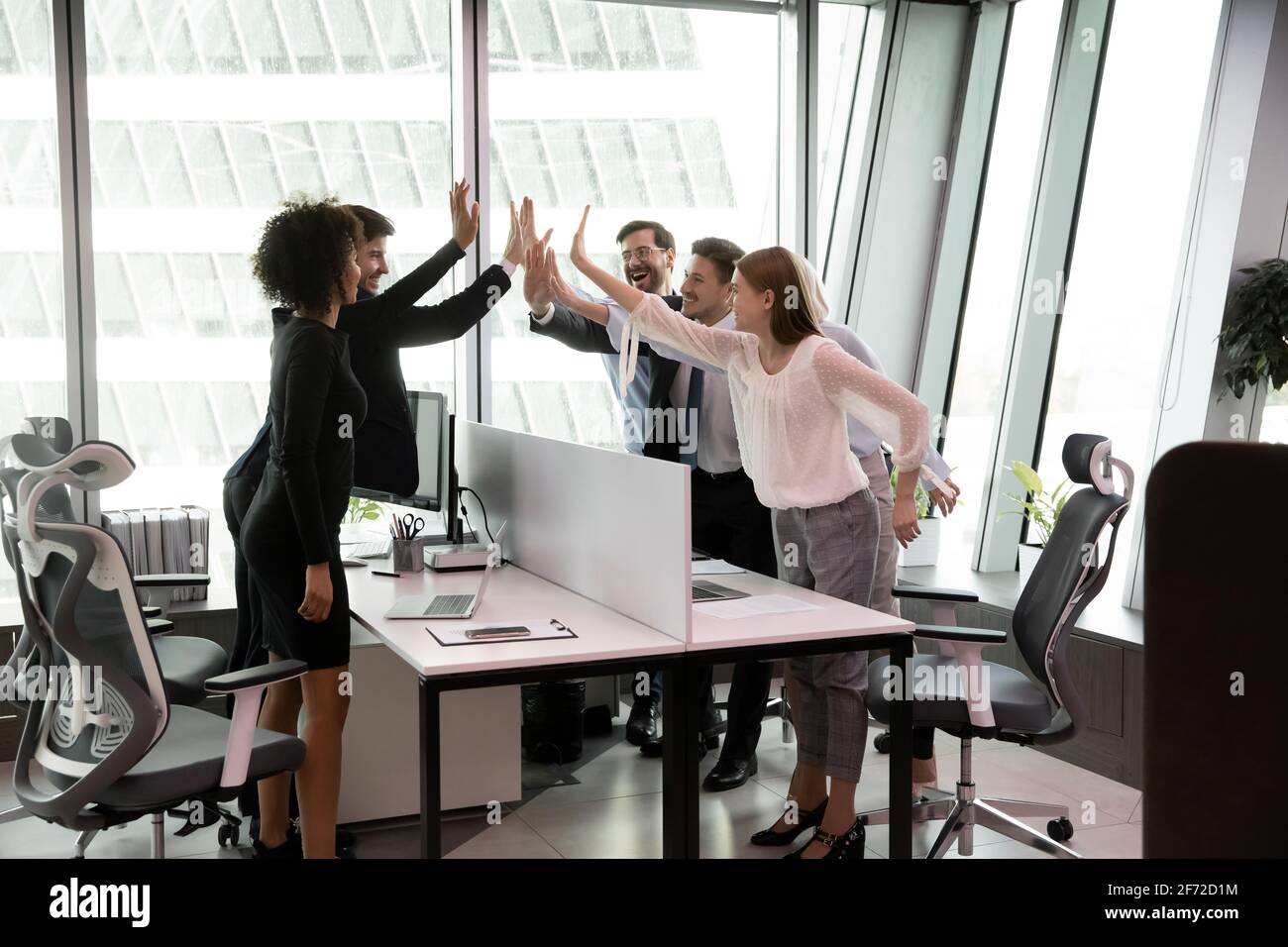 I dipendenti multirazziali entusiasti danno cinque in alto durante la riunione Foto Stock