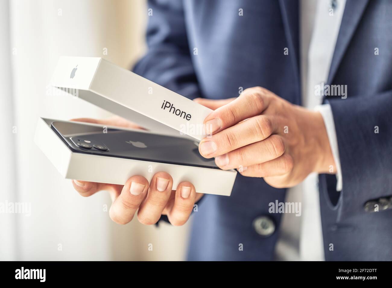 Praga Repubblica Ceca - 2. aprile 2021 - uomo d'affari in tuta tenere in mano e aprire una scatola con una nuova mela nero iphone 12. Foto Stock