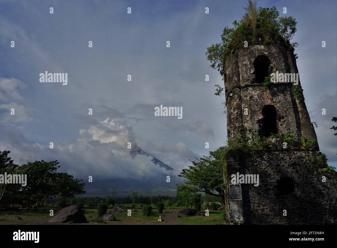 Rovine della chiesa di fronte a una nuvola coperta Mt Mayon Foto Stock