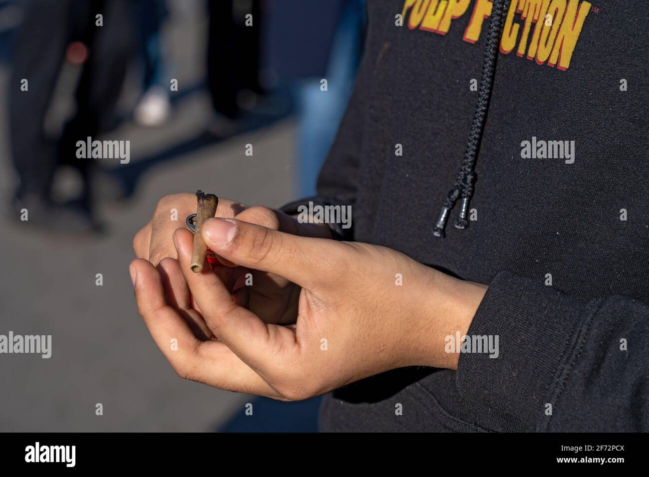 Un New Yorker accende felicemente un giunto nel Washington Square Park.Governor Andrew Cuomo il Mercoledì mattina ha firmato il regolamento Marijuana e legge fiscale approvato dalla legislatura la notte prima di legalizzare la marijuana ricreativa nello stato di New York. Ciò rende New York il 15 ° stato, insieme al Distretto di Columbia, per aver legalizzato il farmaco per uso ricreativo. Foto Stock