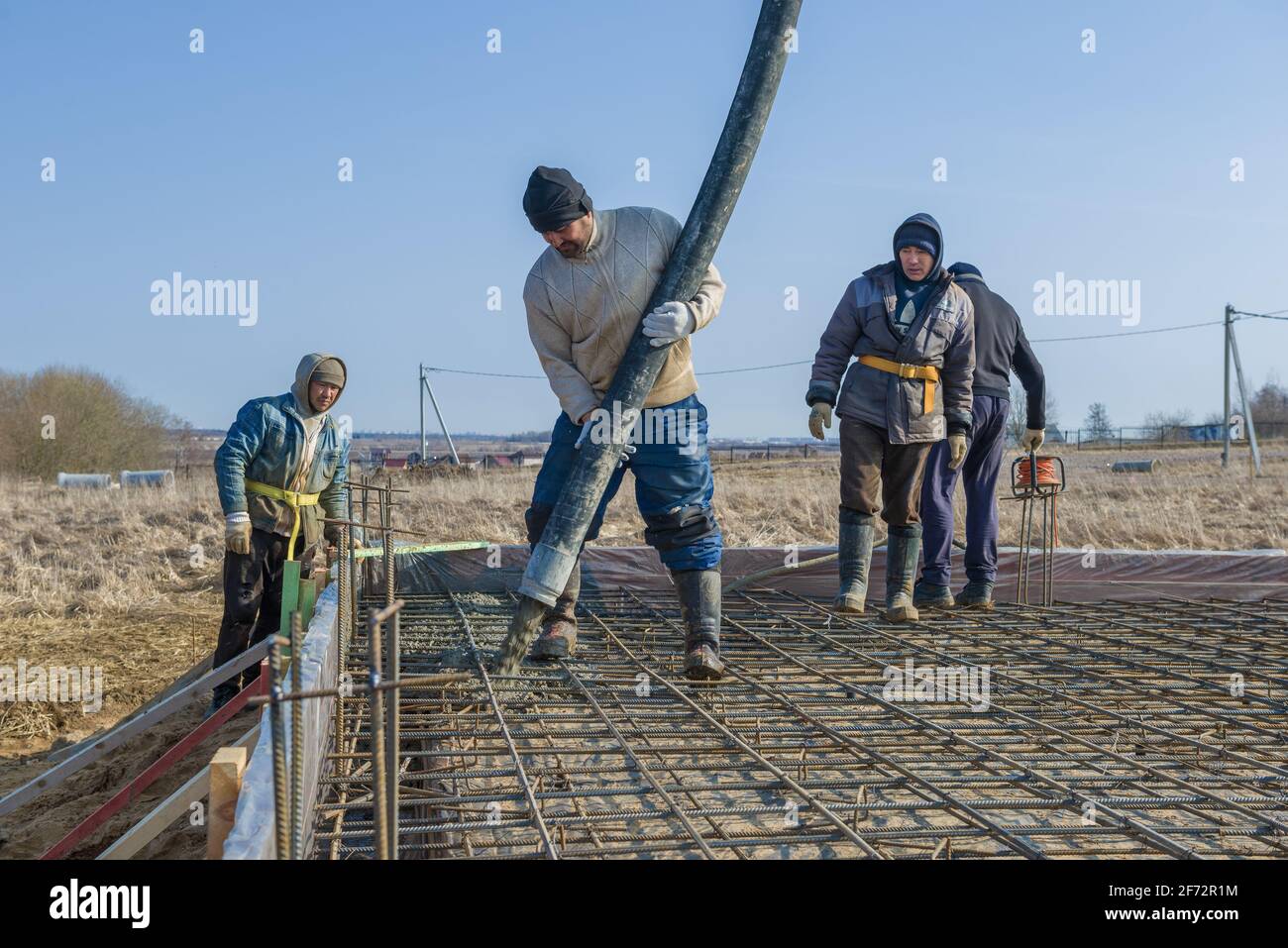 REGIONE DI LENINGRAD, RUSSIA - 28 MARZO 2021: Costruttori - lavoratori migranti versano le fondamenta per la costruzione di una casa di campagna Foto Stock