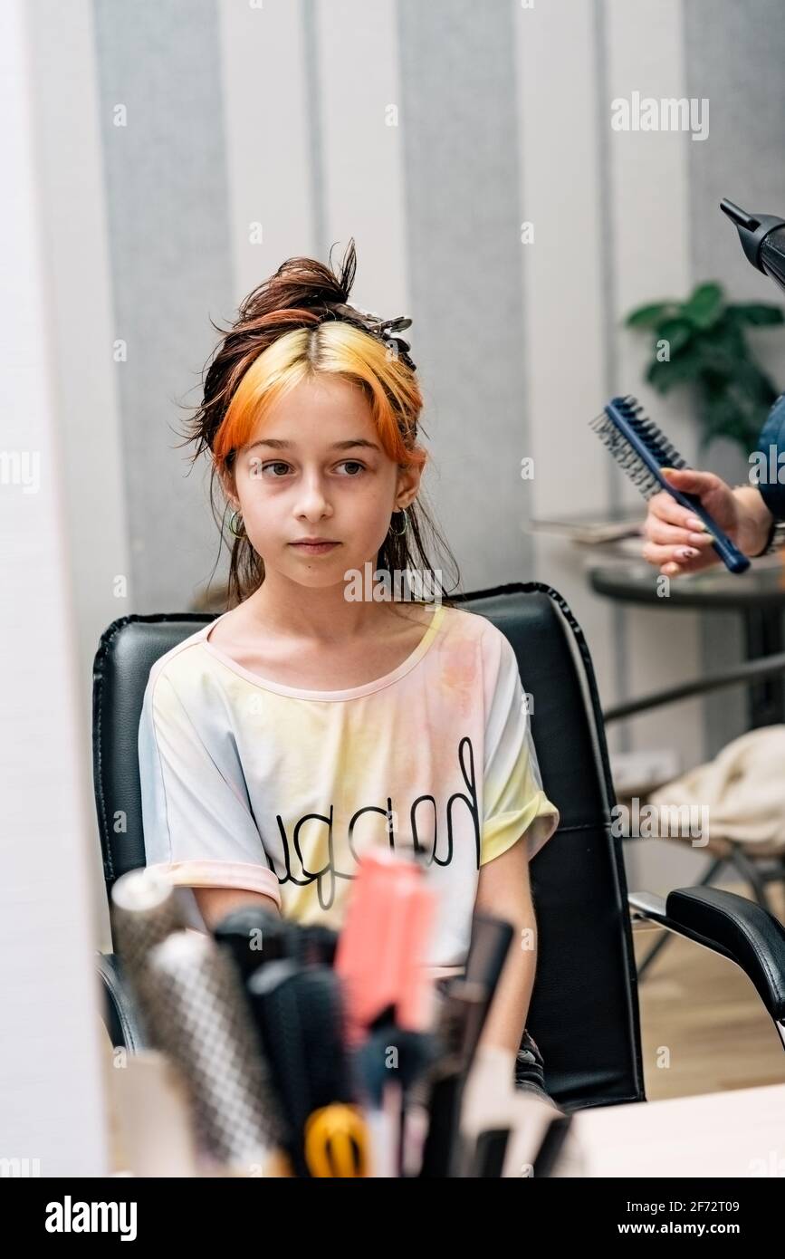 Il parrucchiere tinge i capelli della ragazza nel salone di bellezza. Moda tinteggiato bangs. Capelli sbiancati Foto Stock