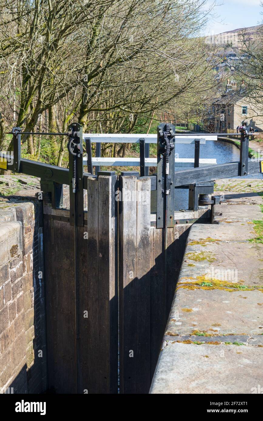 Vista dalla soleggiata molla dei cancelli con serratura e una serratura vuota Camera sullo storico canale stretto di Huddersfield a Marsden in Yorkshire occidentale Foto Stock