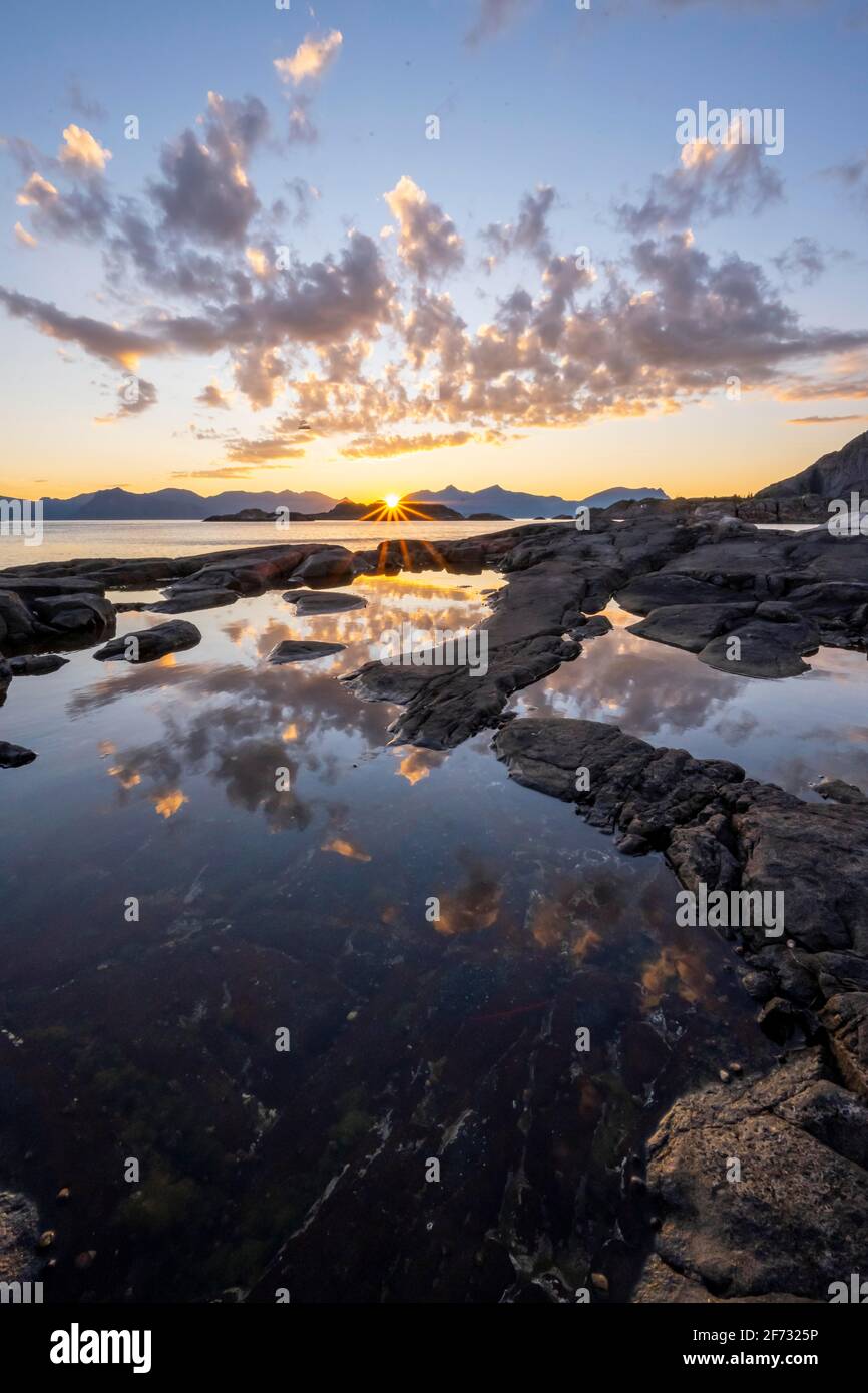 Roccia costa, rocce in piscina marea, tramonto con riflessione nuvola, vicino Henningsvaer, Lofoten, Nordland, Norvegia Foto Stock