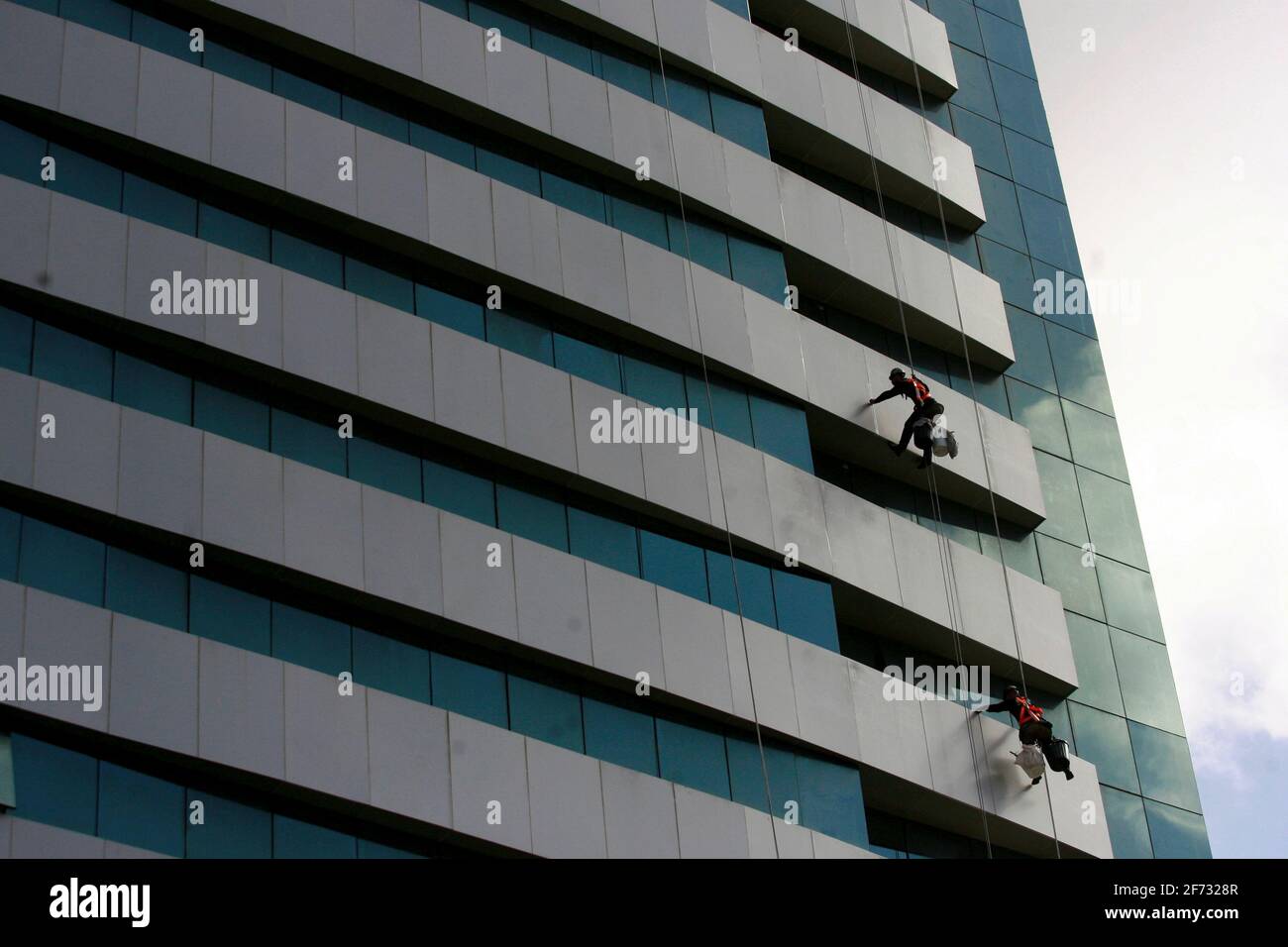 salvador, bahia / brasile - 8 luglio 2016: Gli uomini sono visti appendere da un edificio durante i lavori di pulizia delle finestre nel quartiere di Pituba nella città di SA Foto Stock