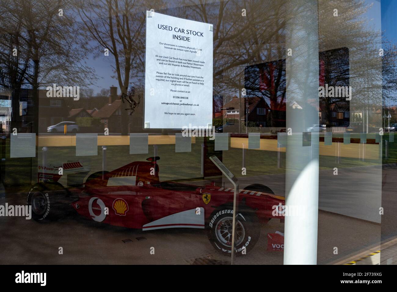 Ferrari F1 Grand Prix racing car all'interno di una concessionaria a Colchester, Essex, Regno Unito, con avviso interno scorte di auto usate. Umorismo. Giustapposizione del segno Foto Stock