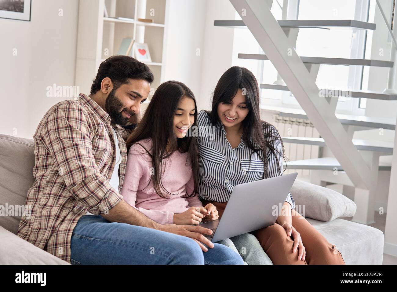 Felice coppia indiana di famiglia con la figlia teen che usa il computer portatile a casa. Foto Stock