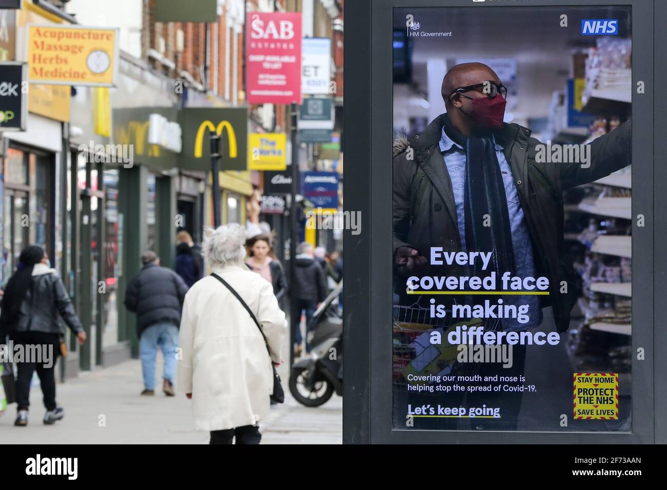 Londra, Regno Unito. 23 marzo 2021. La gente passa davanti al poster Covid-19 che dice "ogni volto coperto fa la differenza" a Londra. Credit: SOPA Images Limited/Alamy Live News Foto Stock