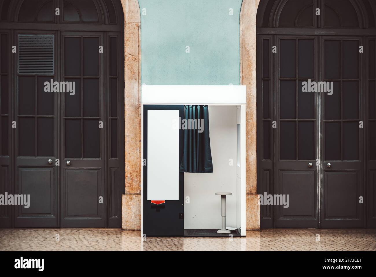 Una cabina fotografica interna vuota con tenda aperta, tra due porte ad arco in legno per la creazione di foto per passaporti e altri documenti, con un punto vuoto Foto Stock