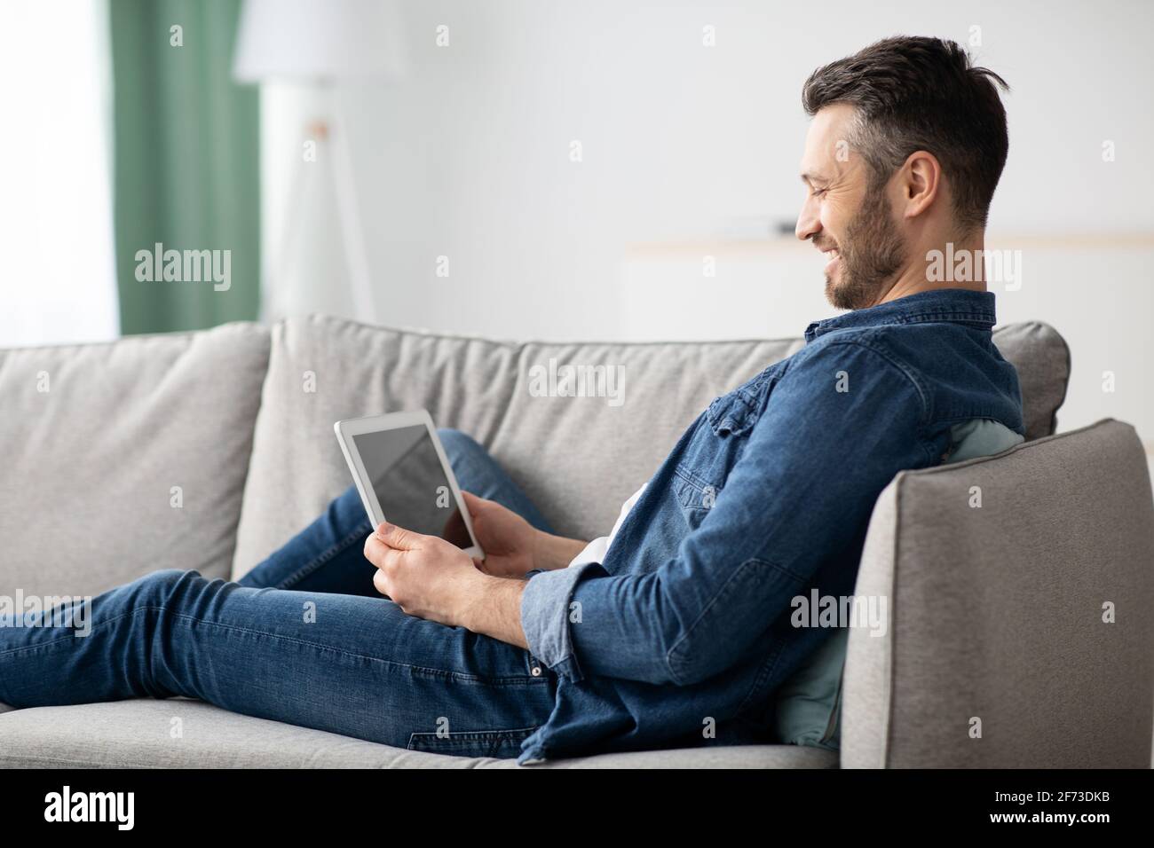 Uomo sorridente con la bearded che usa un tablet digitale con schermo vuoto Foto Stock