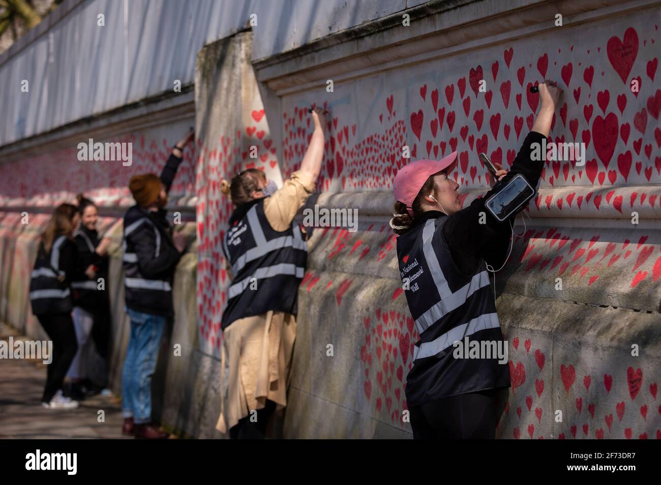 Londra, Regno Unito. 4 aprile 2021. I volontari attirano il cuore la domenica di Pasqua su un muro a Lambeth, vicino al Tamigi, con ogni cuore che rappresenta qualcuno morto durante la pandemia del coronavirus in corso nel Regno Unito. Chiamato il National Covid Memorial Wall, è stato creato dal gruppo chiamato Covid-19 famiglie in lutto per la giustizia con il lavoro che inizia una settimana fa e si estende per mezzo miglio per il momento in cui è completo. Credit: Stephen Chung / Alamy Live News Foto Stock