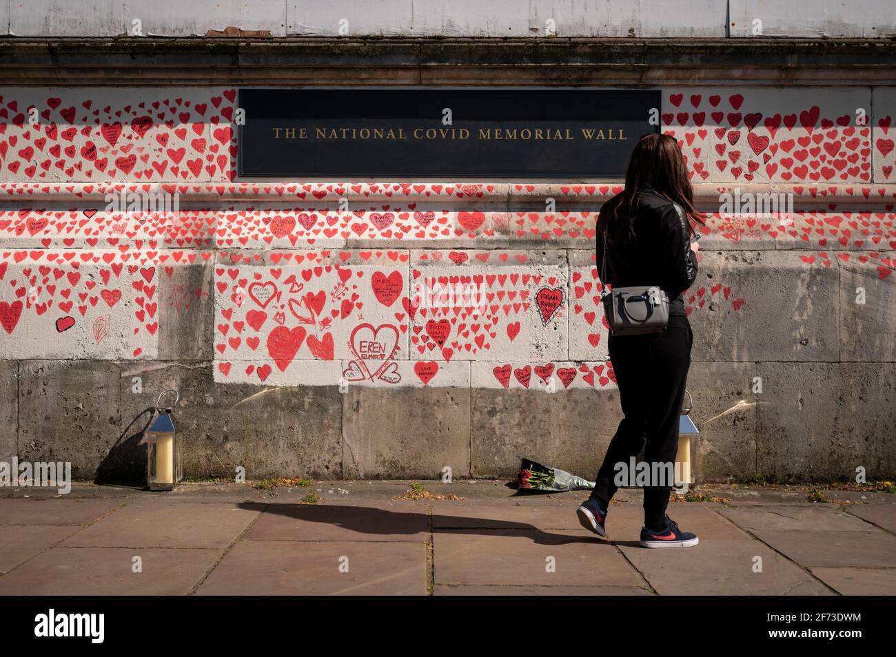 Londra, Regno Unito. 4 aprile 2021. Una donna vede i cuori la domenica di Pasqua su un muro a Lambeth, vicino al Tamigi, con ogni cuore che rappresenta qualcuno che è morto durante la pandemia di coronavirus in corso nel Regno Unito. Chiamato il National Covid Memorial Wall, è stato creato dal gruppo chiamato Covid-19 famiglie in lutto per la giustizia con il lavoro che inizia una settimana fa e si estende per mezzo miglio per il momento in cui è completo. Credit: Stephen Chung / Alamy Live News Foto Stock