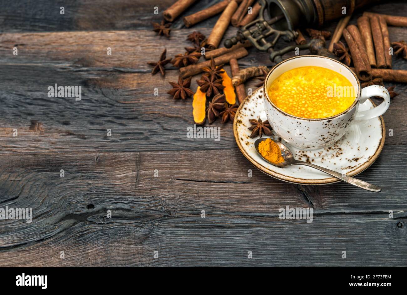 Bevanda curcuma calda con spezie su rustico sfondo di legno Foto Stock
