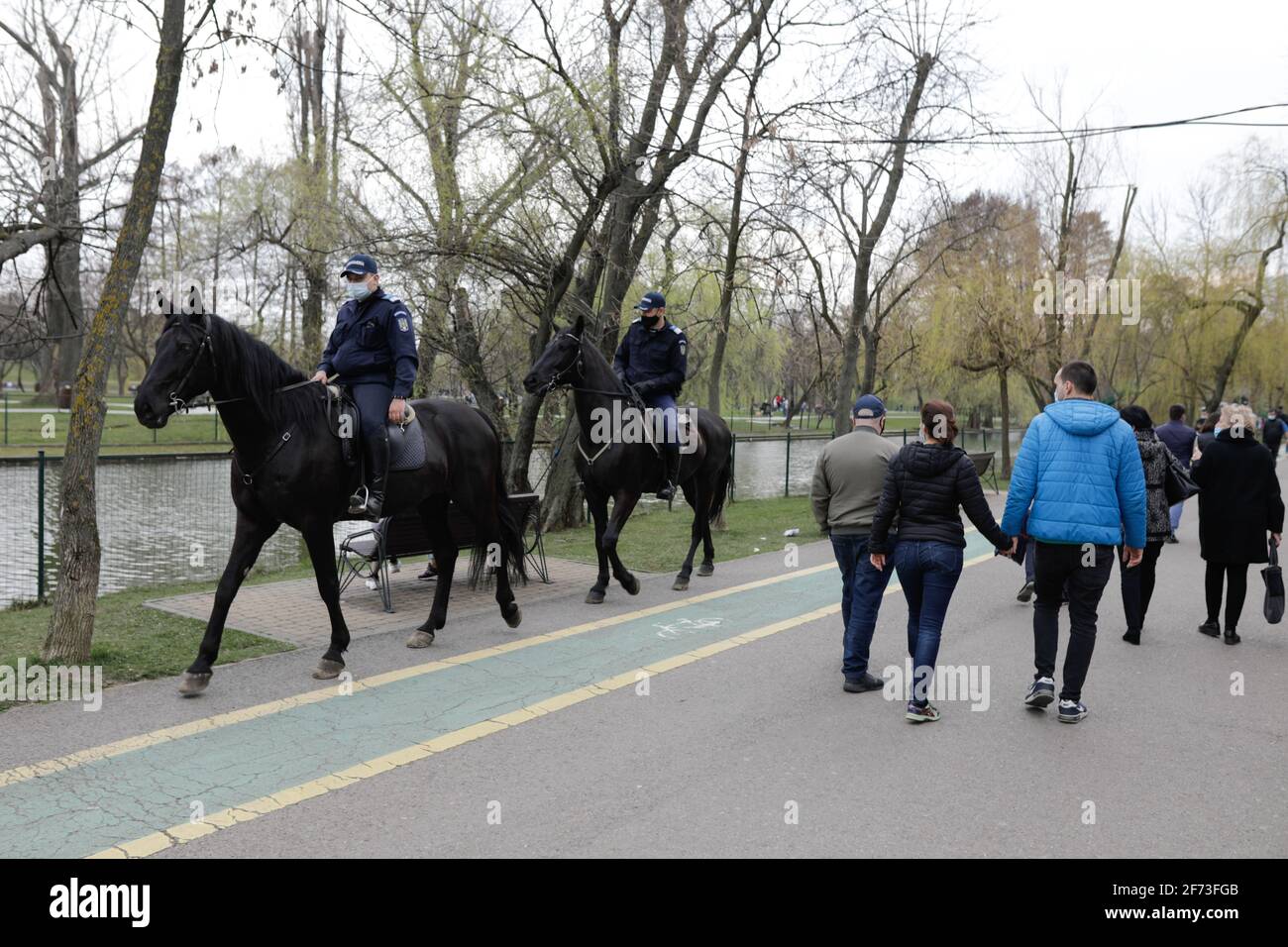 Bucarest, Romania - 28 marzo 2021: Jandarmi rumeni sui cavalli pattugliano il parco IOR a Bucarest durante le restrizioni pandemiche di Covid-19. Foto Stock