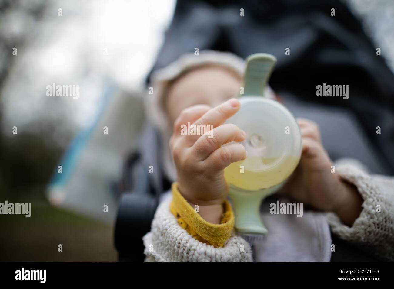 Immagine della profondità di campo bassa (messa a fuoco selettiva) con le mani di un bambino che tiene un biberon. Foto Stock