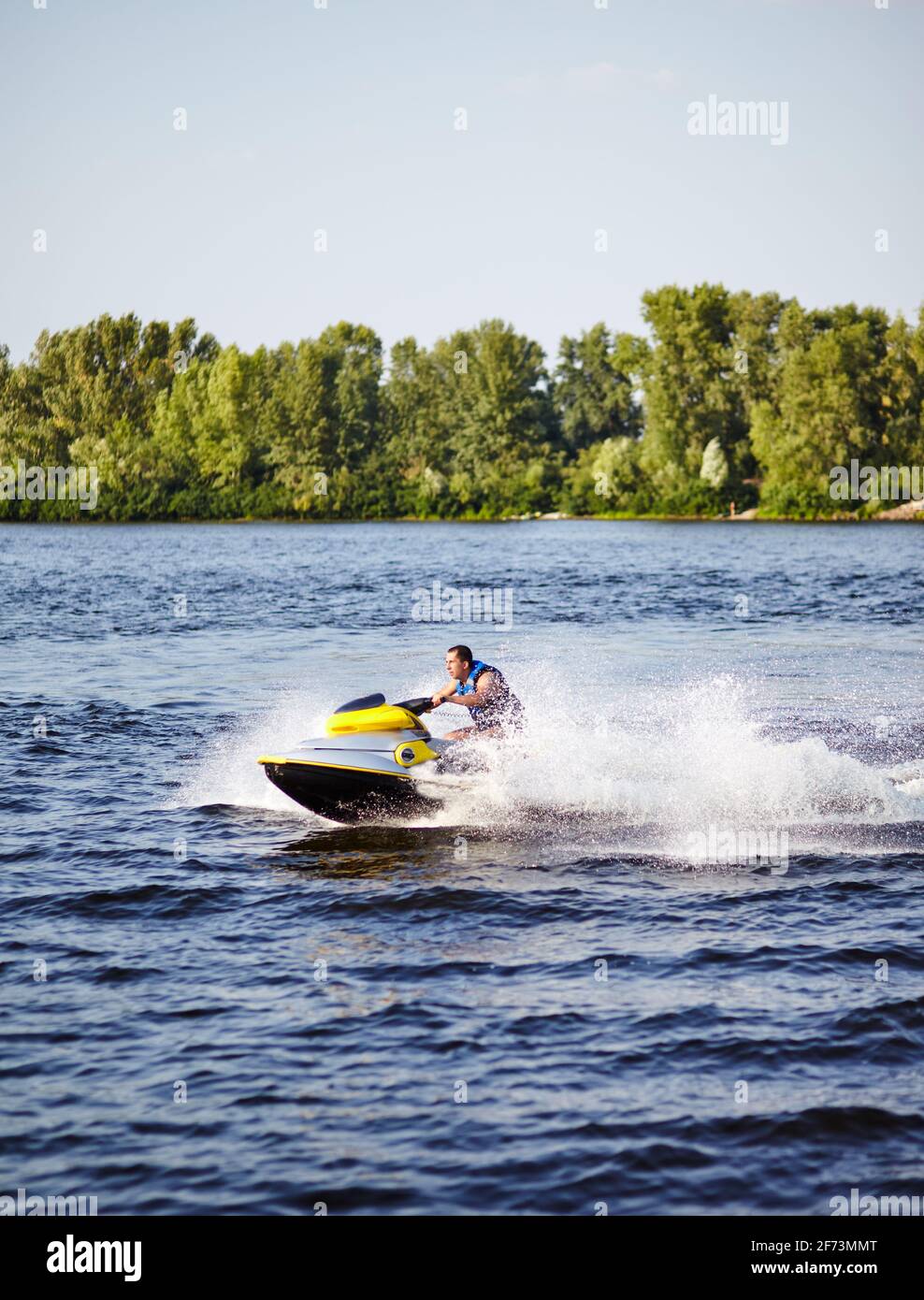 L'uomo forte salta sul jetski sopra l'acqua. Uomo che accelera su moto d'acqua sul lago durante le vacanze estive Foto Stock