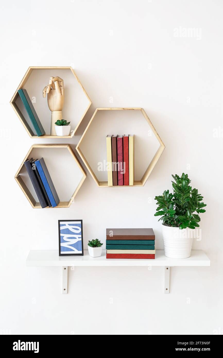 Mensole con libri e decorazioni appese su pareti chiare Foto stock