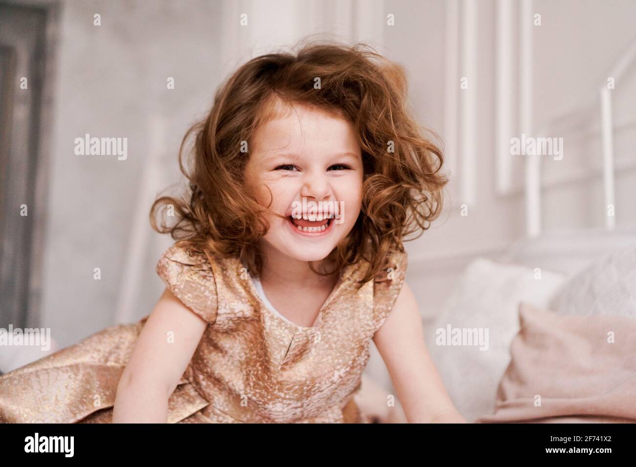 Ritratto di una ragazza felice di tre anni. Il bambino dai capelli biondi ride Foto Stock