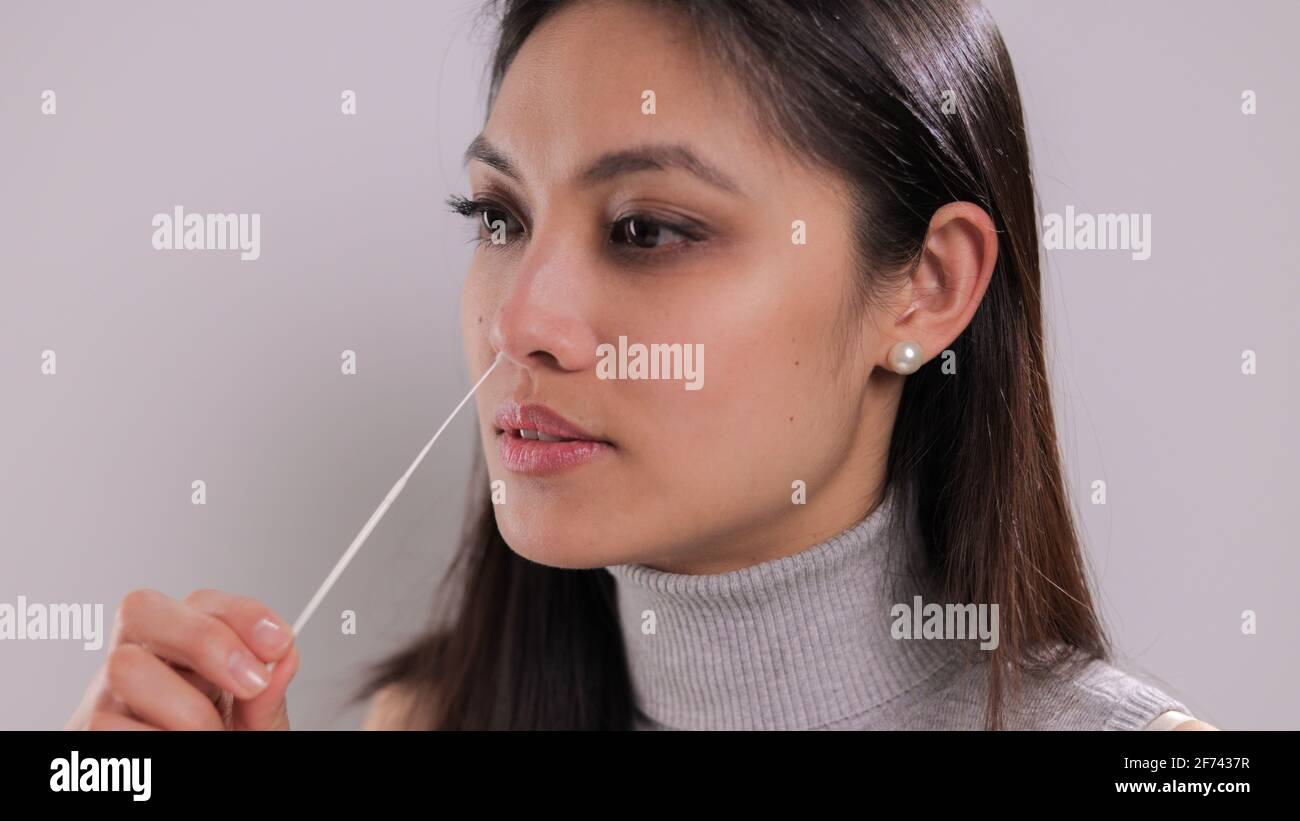 Giovane donna prende un campione dal suo naso per un test corona Foto Stock