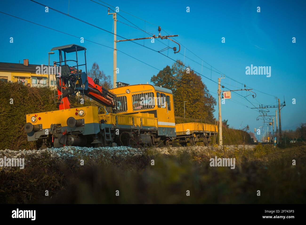 Treno da lavoro giallo su una leggera curva, che si arrossa per fissare i binari del treno. Foto Stock