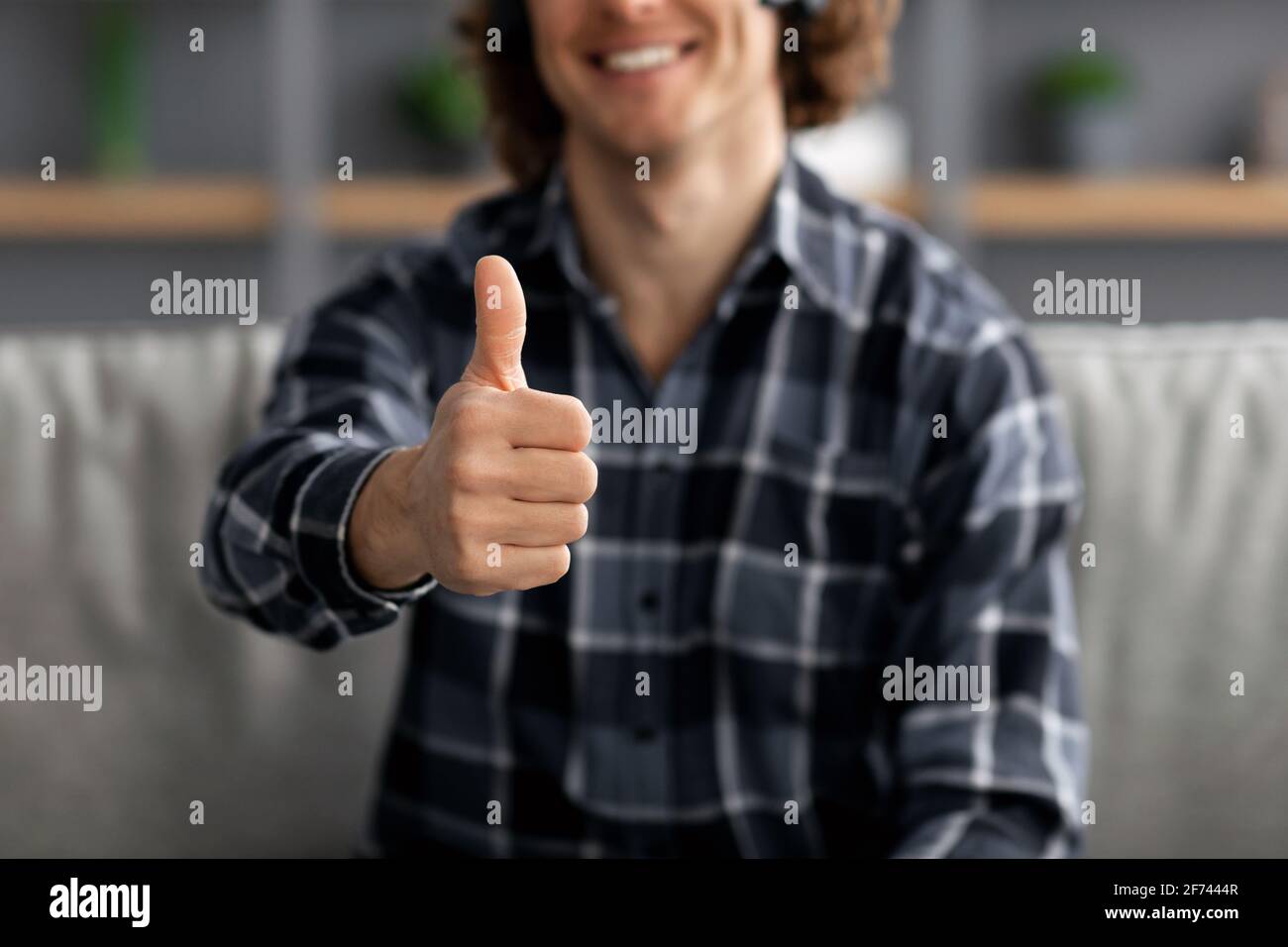 Guy gesturing Thumbs-Up approvando qualcosa che siede a casa, ritagliato Foto Stock