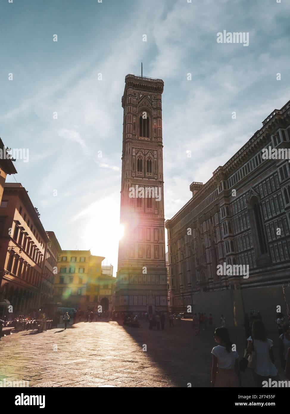 Firenze, Italia - 12 agosto 2019: Il campanile di Giotto e la Cattedrale di Santa Maria del Fiore si affacciano sulla strada con il sole luminoso. Facciata in marmo colorato con co Foto Stock