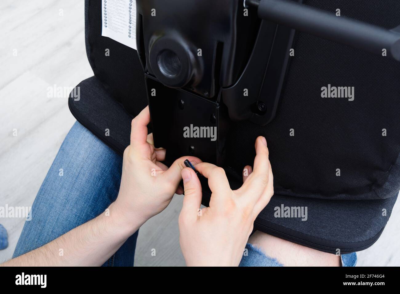 Meccanismo di sollevamento sedia a vite uomo caucasico. Montaggio della sedia da ufficio Foto Stock