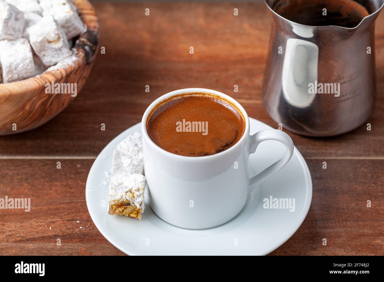 Caffè turco tradizionale servito in tazzine classiche con delizie turche. Sullo sfondo è presente una caffettiera in metallo. Foto Stock